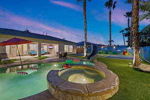 An outdoor pool area with a hot tub, lounge chairs, and a slide. - All Inclusive  Super Mario Hideout Arcade PIckleball Pool Slide (Indio)