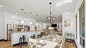 A modern kitchen with white cabinetry, stainless steel appliances, and pendant lighting. - All Inclusive  Super Mario Hideout Arcade PIckleball Pool Slide (Indio)
