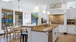 A modern kitchen with a large island, white cabinetry, granite countertops, and pendant lighting. - All Inclusive  Super Mario Hideout Arcade PIckleball Pool Slide (Indio)