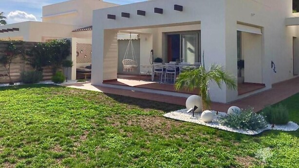 A modern house with a patio area featuring outdoor furniture and a hanging chair. - Villa DE Alquiler Perdiz (Dehesa de Campoamor)
