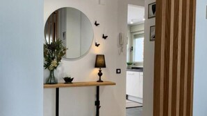 A modern interior with a round mirror, a small table with a lamp, and a wooden panel. - Villa DE Alquiler Perdiz (Dehesa de Campoamor)