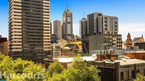 A cityscape with modern high-rise buildings, a historic clock tower, and a construction crane. - Central Studio in the Heart of Melbourne Cbd! (Melbourne)
