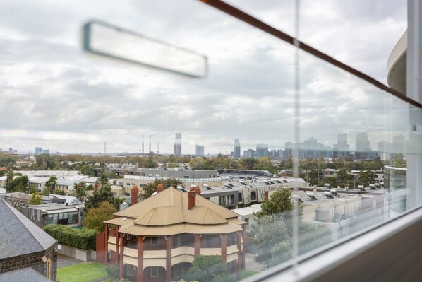 A view from a window overlooking a cityscape with various buildings, including a distinctive curved building in the foreground.