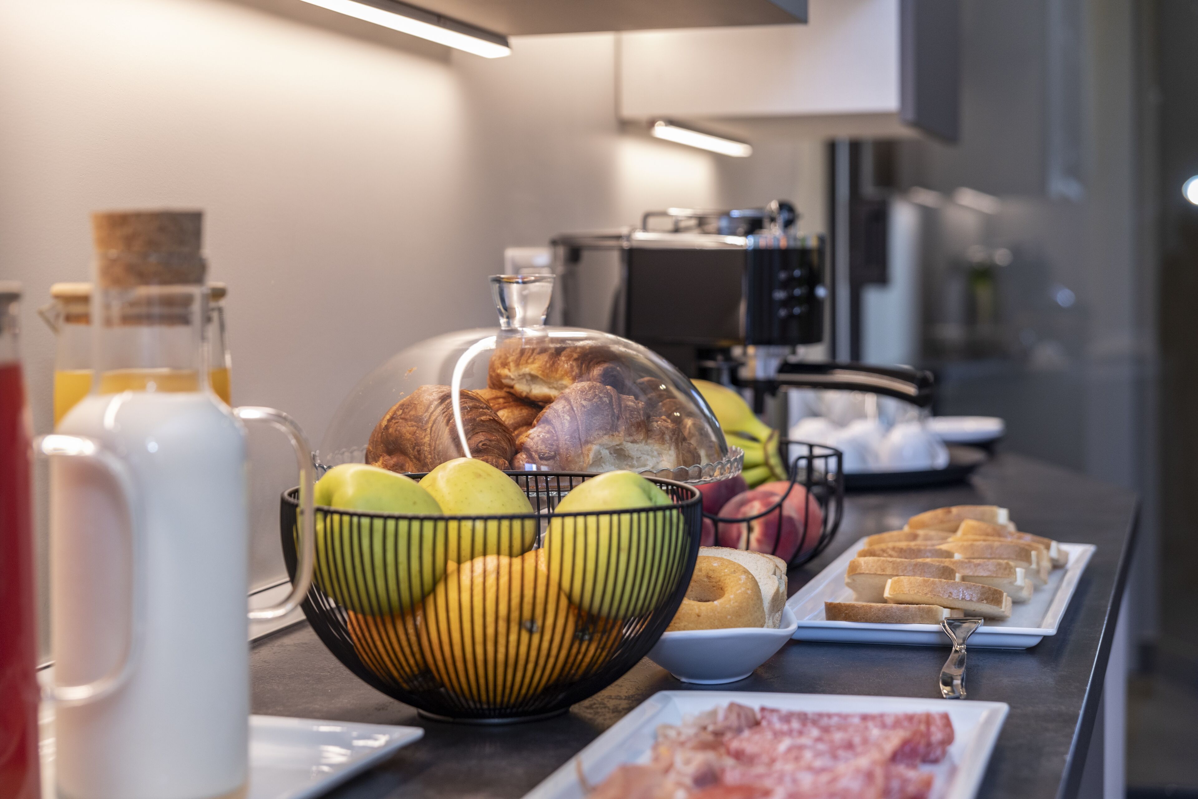 Buffet de café da manhã com diversos itens, incluindo frutas, doces e pão.