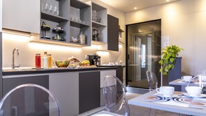 A modern kitchen with built-in shelves, a coffee station, and a dining area with clear chairs and a table. - Trastevere 143 (Rome)