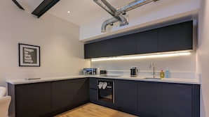 Eine moderne Küche mit dunklen Schränken, einem eingebauten Ofen, einer Mikrowelle und einer Kaffeemaschine.