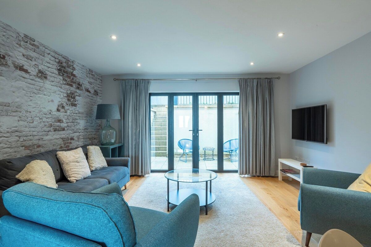 A modern living room with a brick wall, a sofa, a coffee table, and a TV.