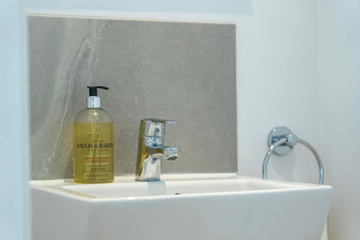Un lavamanos de baño con una botella de jabón líquido Baylis & Harlans y un grifo cromado.