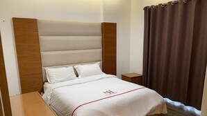 A hotel room with a bed, wooden headboard, nightstands, and a window with curtains. - New Home Residence (Beirut)