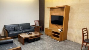 A modern living room with a sofa, coffee table, TV stand, and wooden chairs. - New Home Residence (Beirut)