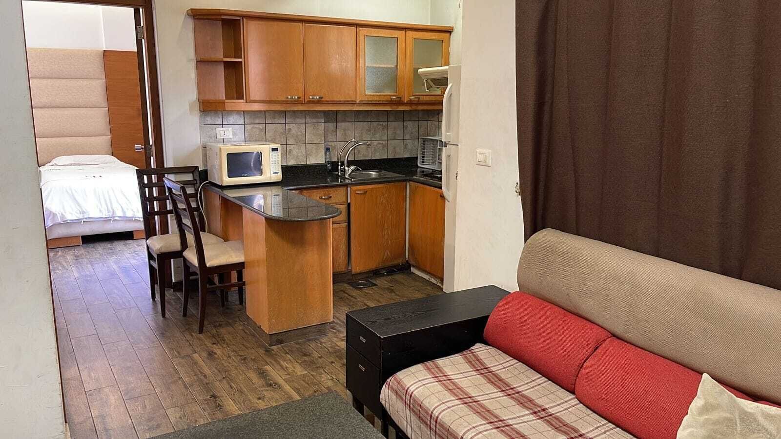 A compact living space with a kitchenette, a dining area, and a bed.