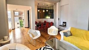 A modern living room with a yellow sofa, white chairs, and a dining area with red chairs. - Appartement Design Rouen-gare Parking-netflix, 3 Chambres, 2 Salles de Bains (Rouen)