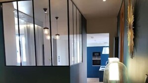 A modern interior with a wooden floor, a glass partition, and a table with a lamp. - Appartement Design Rouen-gare Parking-netflix, 3 Chambres, 2 Salles de Bains (Rouen)