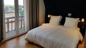 A bedroom with a large bed, two bedside lamps, a view through a sliding door to an outdoor area, and a dark ceiling. - Appartement Design Rouen-gare Parking-netflix, 3 Chambres, 2 Salles de Bains (Rouen)