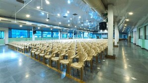 A spacious hall with rows of plastic chairs, large windows, and a high ceiling with lighting fixtures. - Hotel Merlin Interantional (Thrissur)