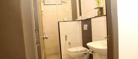 Casa de banho compacta com sanita, lavatório e zona de duche.