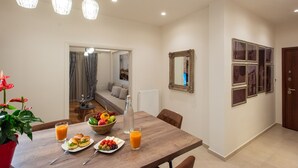 Uma sala de jantar com uma mesa de madeira, cadeiras, uma tigela de frutas e copos de suco.