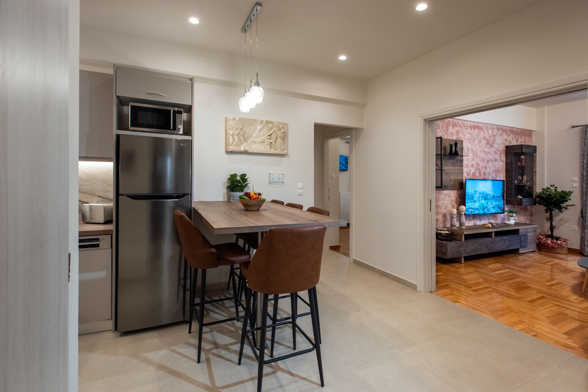 Una cocina moderna con un refrigerador de acero inoxidable, un microondas y una mesa de comedor de madera con cuatro sillas.