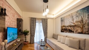 Uma sala de estar moderna com um sofá, uma televisão, uma mesa de centro e um quadro na parede.