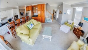 A spacious living area with a sofa, coffee table, and a dining area with chairs and a kitchen in the background. - BAY FRONT HOME WITH AMAZING VIEWS.  MINUTES TO THE BEACH AND STEPS TO THE POOL  (Fenwick Island)