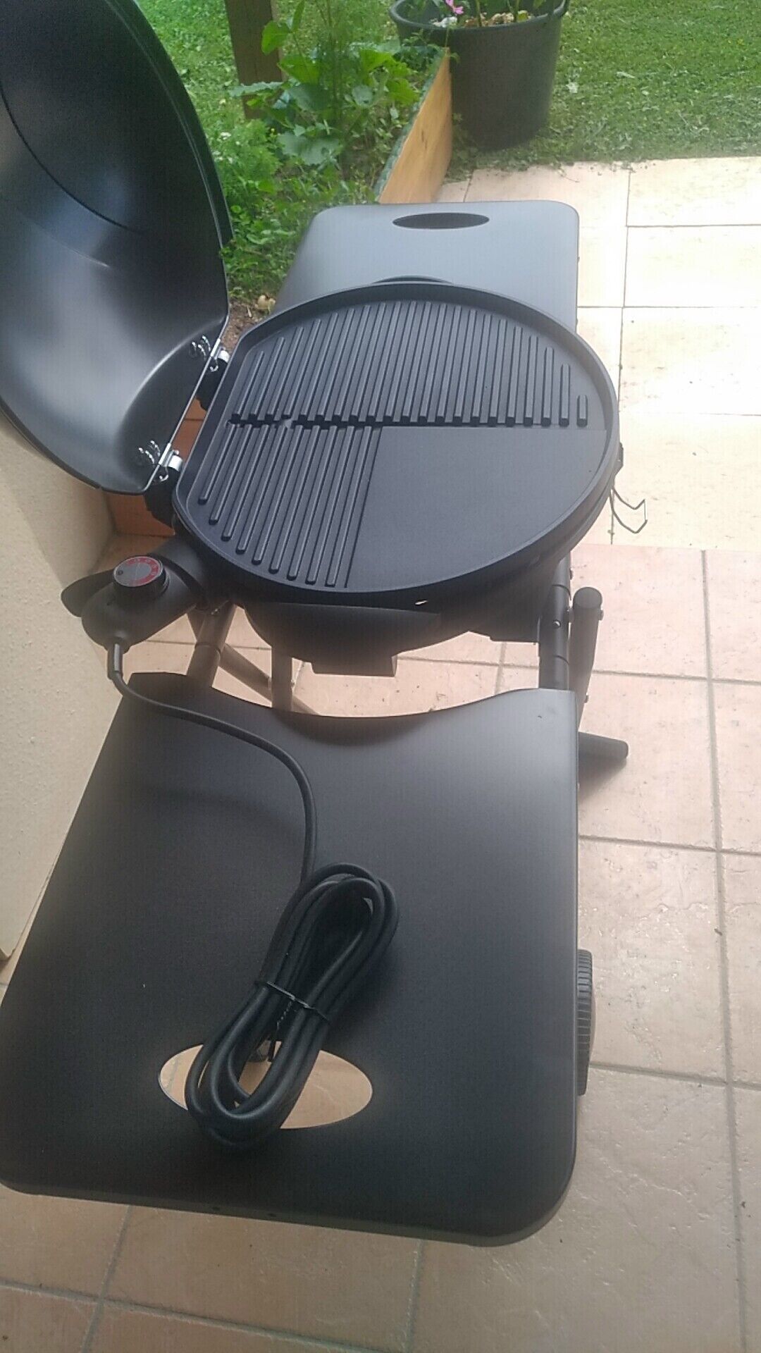 A portable grill with a control panel and a power cord.