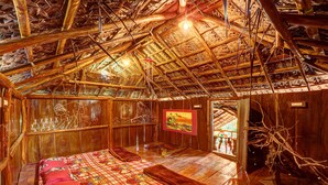 Une pièce rustique en bois, avec un plafond haut, un lit recouvert d’une courtepointe à carreaux et un tableau accroché au mur.