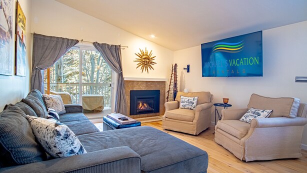 En moderne stue med pejs, behagelige siddepladser og et stort tv, der viser 'Michael's Vacation Rentals'.