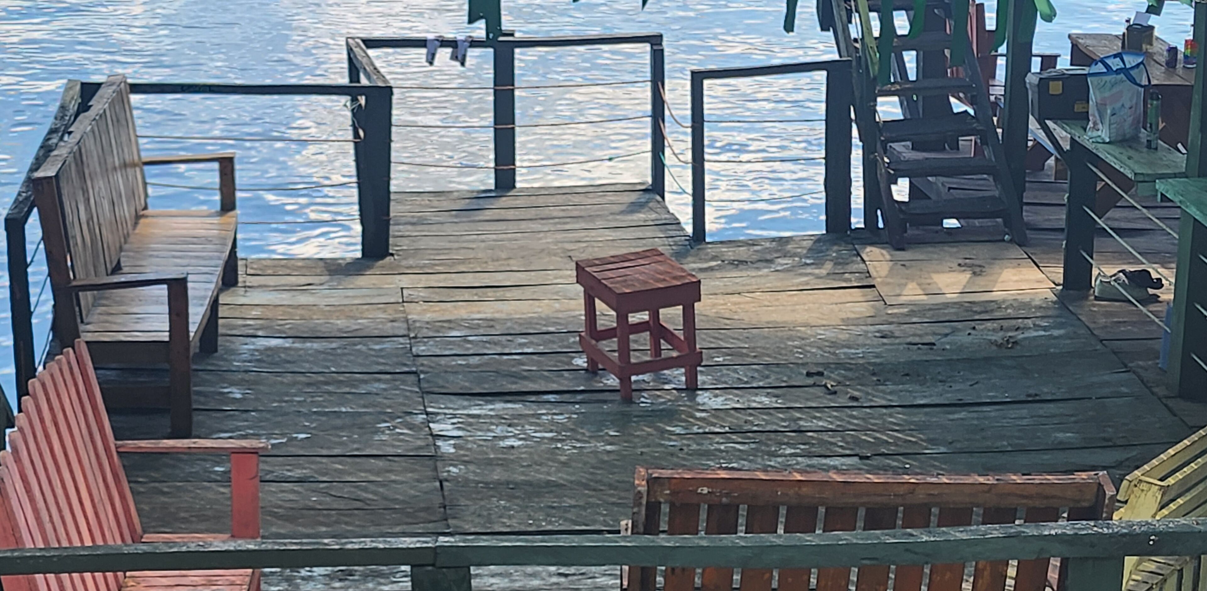 A wooden pier with benches and a small table.