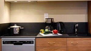 A kitchen with a stove, a dishwasher, wooden cabinets, and a countertop with vegetables.