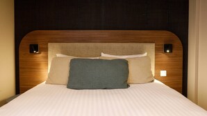 A bed with a wooden headboard, two pillows, and a bedside table.