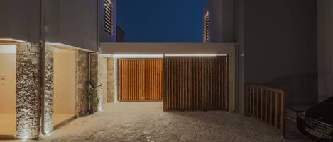 A modern building with a stone facade, a wooden gate, and a car parked outside.