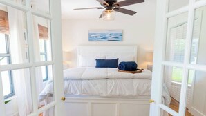 Una camera da letto con un letto, una ventola a soffitto, un quadro e una finestra.