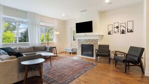 A living room with a fireplace, a television, and a sofa. - 3BR Hillsboro Home · Sleeps 6 · Intel · Pets OK (Hillsboro)