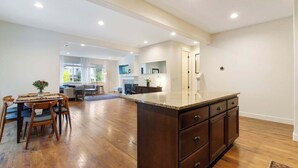 A spacious kitchen with a large island, wooden flooring, and a dining area with a table and chairs. - 3BR Hillsboro Home · Sleeps 6 · Intel · Pets OK (Hillsboro)
