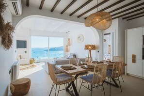 A modern dining area with a large table, wicker chairs, and a view of the sea. - My Rental Homes - Villa Sonia with pool, Jacuzzi bathtub, sea view (Platis Gialos)