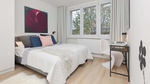 Un dormitorio moderno con una cama, un escritorio y un ventanal grande.