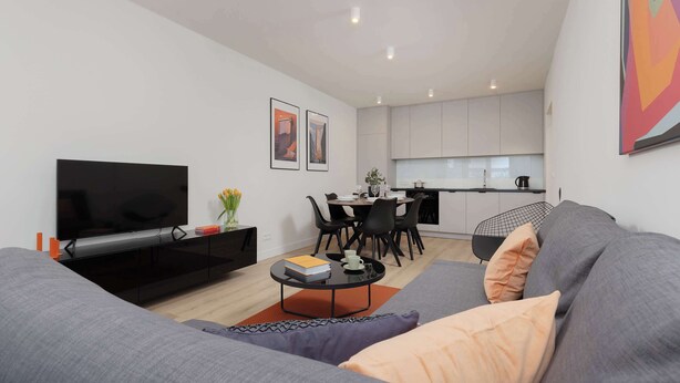 Una sala de estar moderna con un televisor de pantalla plana, un sofá gris y una mesa de centro.