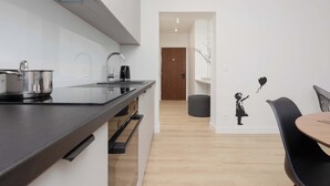 Una cocina moderna con encimera negra, electrodomésticos de acero inoxidable y una puerta de madera al fondo.