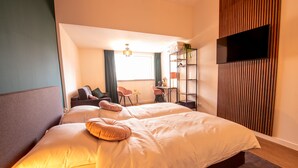 Una habitación de hotel moderna con una cama grande, un escritorio y un televisor montado en la pared.