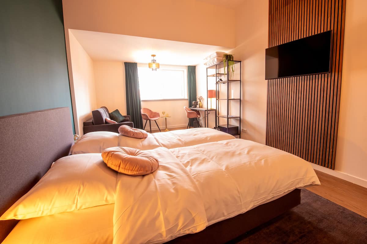 A modern hotel room with a large bed, a desk, and a TV mounted on the wall.