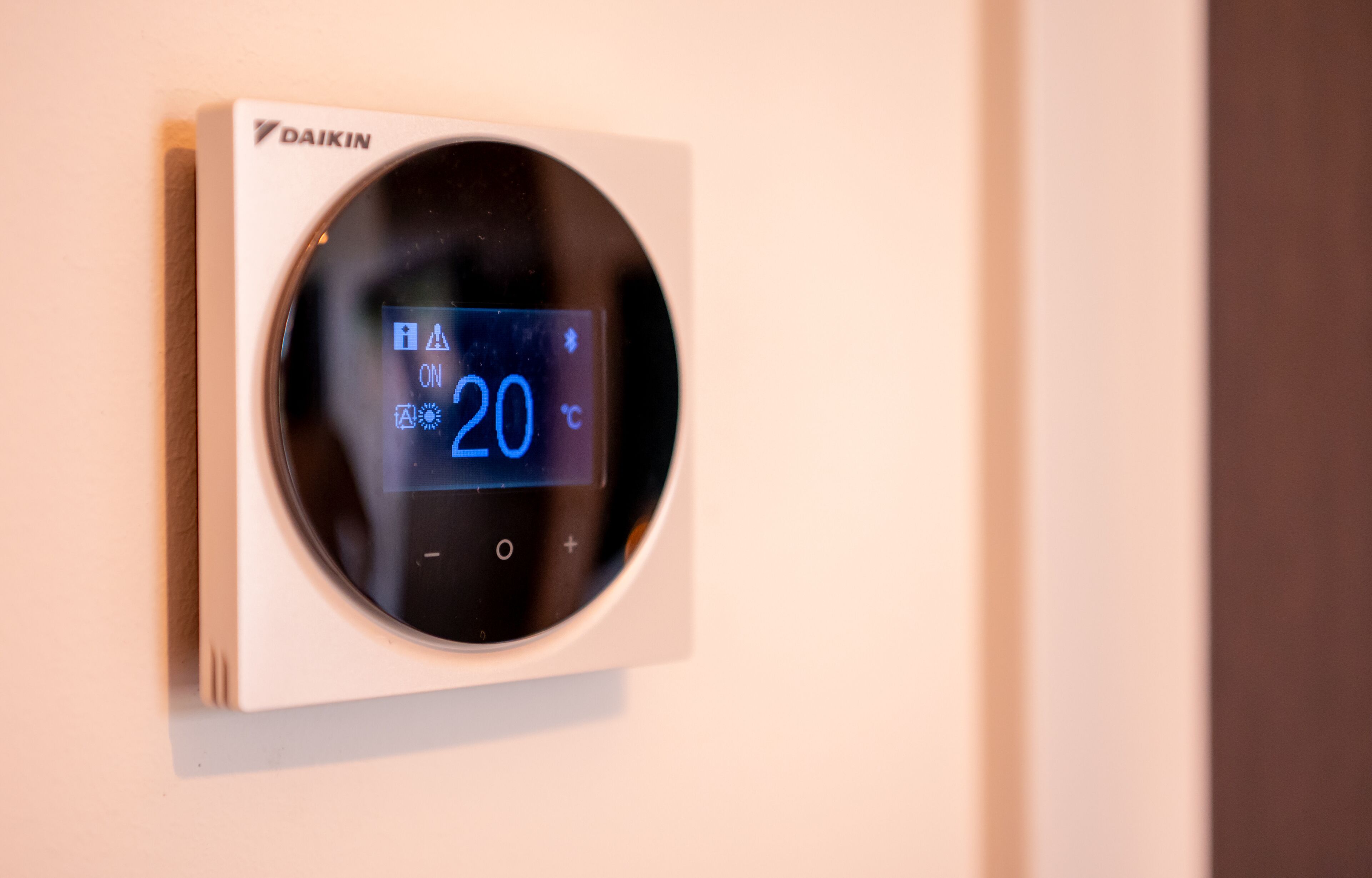 A wall-mounted thermostat displaying a temperature of 20°C.