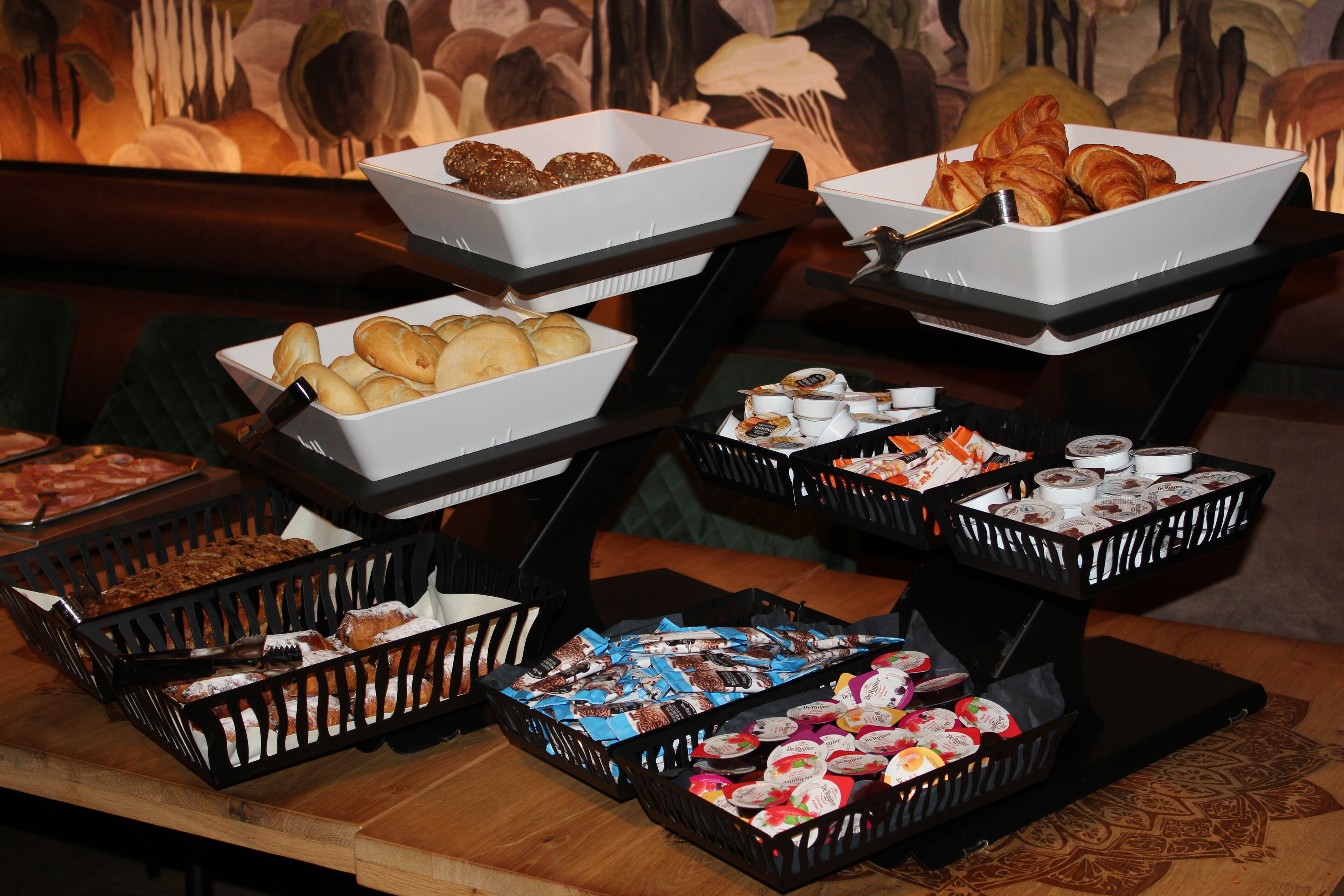 A buffet with various food items including pastries, bread, and desserts.