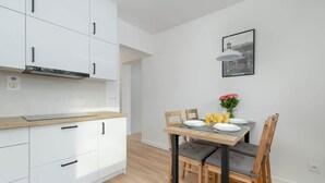 A modern kitchen with white cabinets, a wooden countertop, and a dining area with a table set for two. - Apartment with a View of the Tatra Mountains | Balcony | 600 m to the Center (Zakopane)