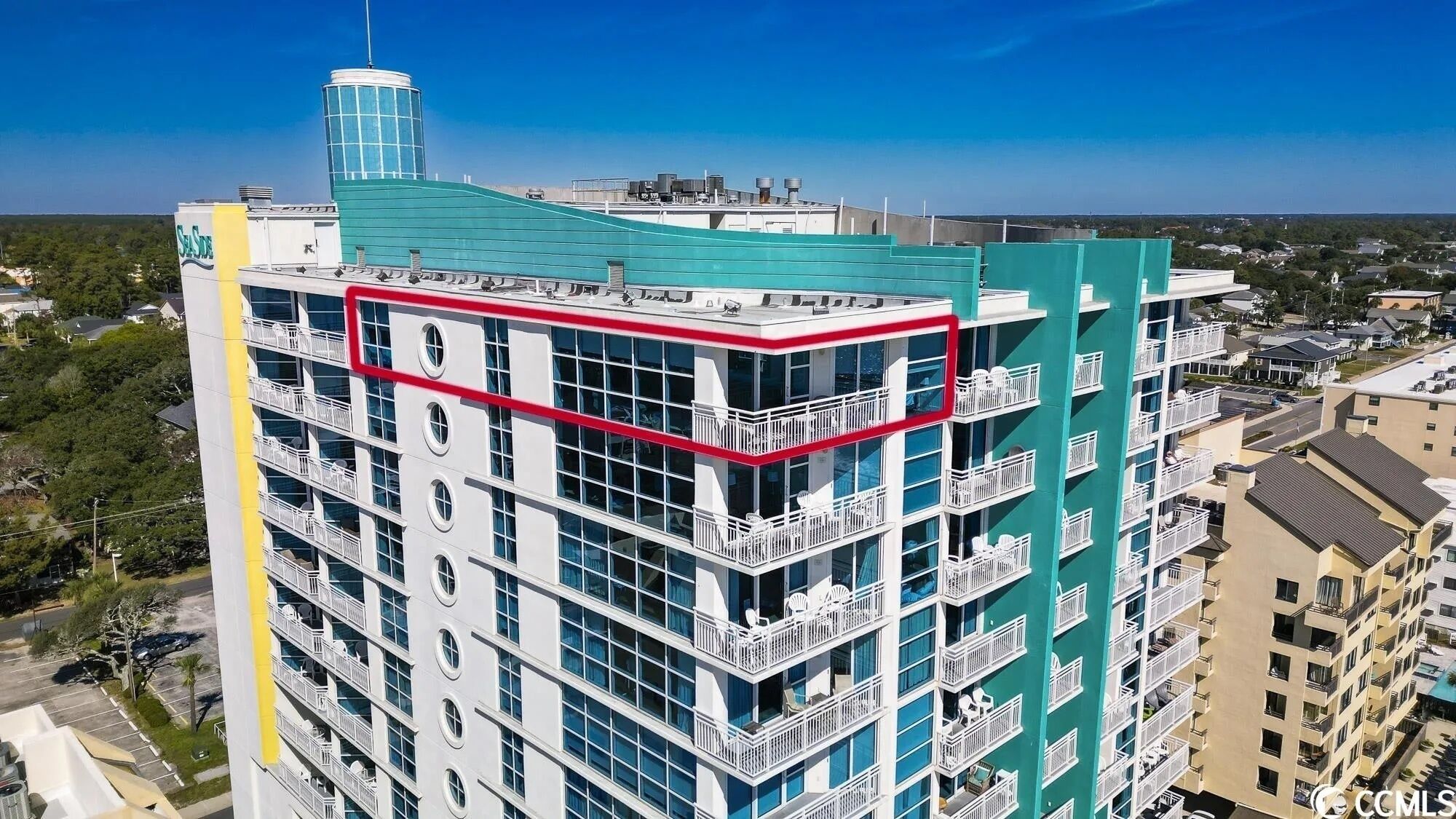 A multi-story hotel with balconies, a rooftop pool, and a view of the surrounding area.