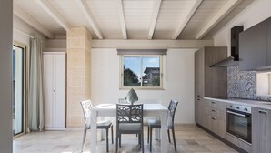 Eine moderne Küche mit Essbereich, mit großem Fenster, eingebauten Schränken und einer Steinwand.