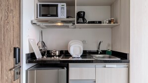 A compact kitchen with a microwave, coffee maker, and a sink. - DAS HAUS  (Bogotá)