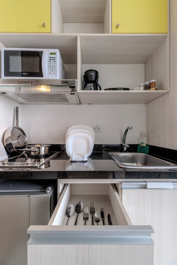 Une cuisine compacte équipée d’un four à micro-ondes, d’une machine à café et d’un four encastré.