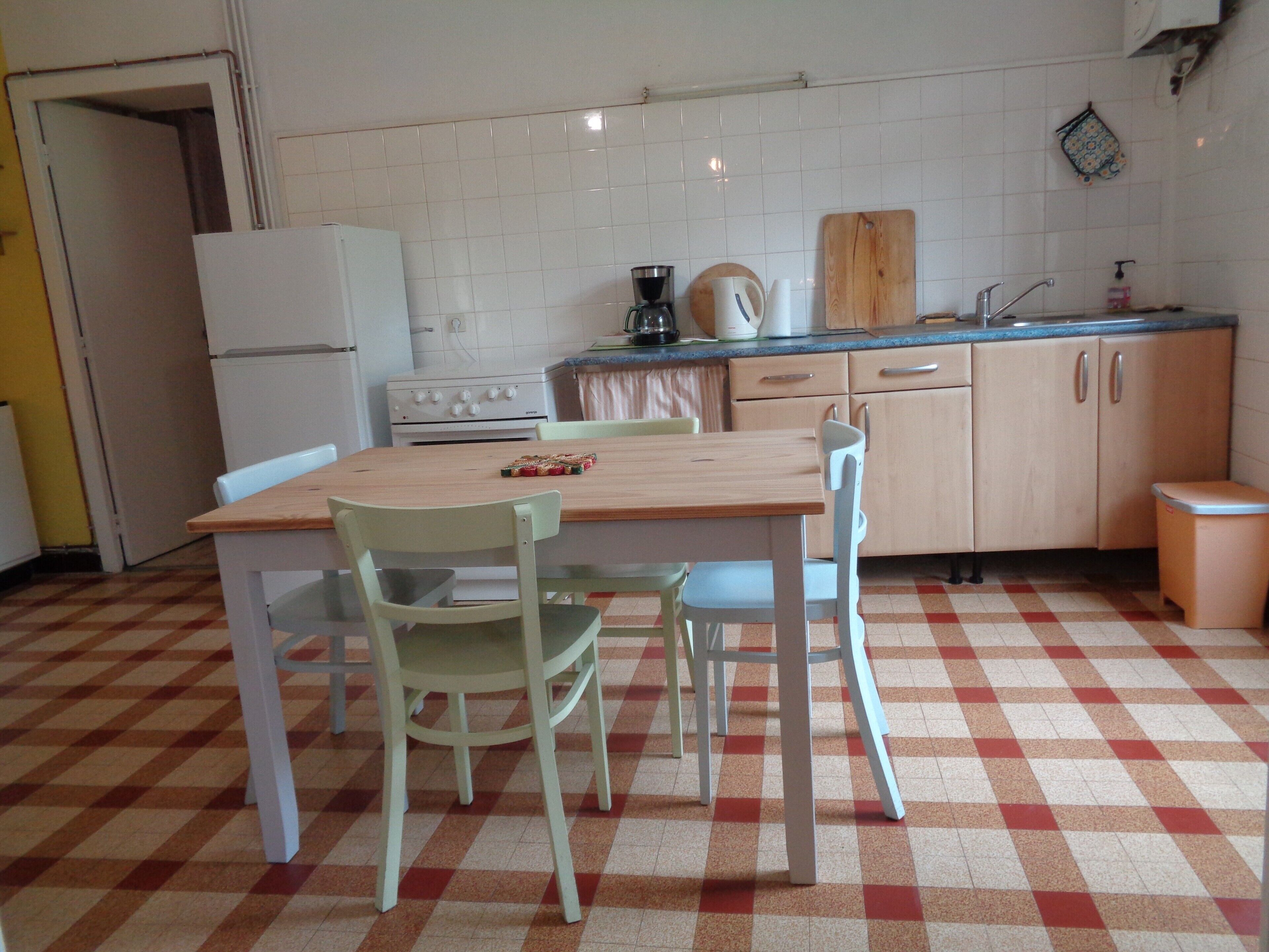 A kitchen with a checkered floor, a wooden table, and light-colored chairs.
