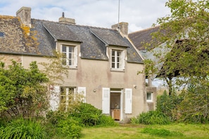A two-story house with a sloped roof, white shutters, and a small front porch.