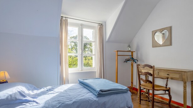 A bedroom with a bed, a desk, a chair, a window with curtains, and a mirror on the wall. - Small House 5min Drive from Beach with Private Terrace and Garden (Plobannalec-Lesconil)